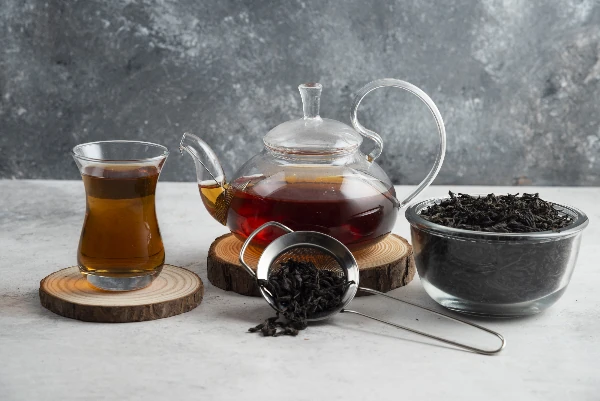 a glass teapot with earl grey tea on a wooden board