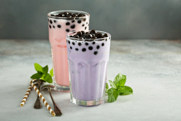 taro milk tea and strawberry milk bubble tea in tall glasses