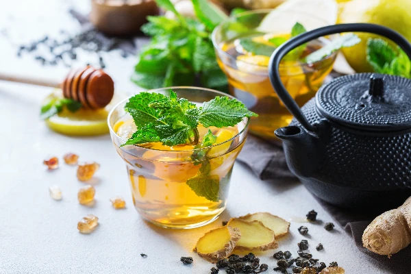 teapot and glass with spearmint tea on table with lemon, ginger and mint