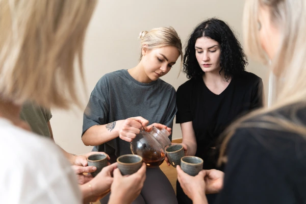 woman pouring tea to her friends to avoid dehydration