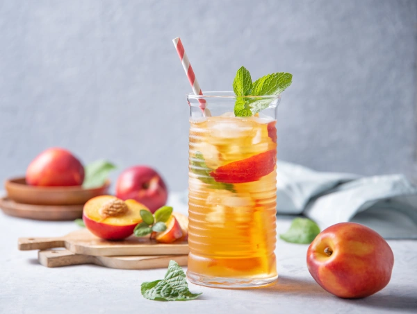 cool peach tea with mint and ice in a glass