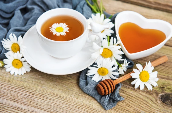 cup of chamomile tea and chamomile flowers