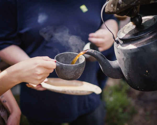 pouring hot kava tea into cup